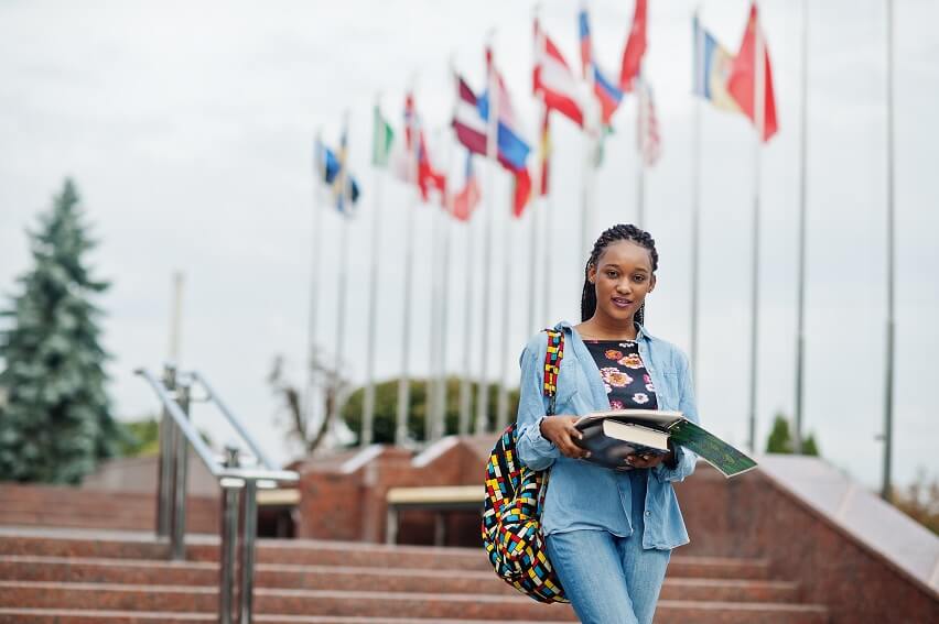 african student female posed with backpack school items yard university against flags different countries 1